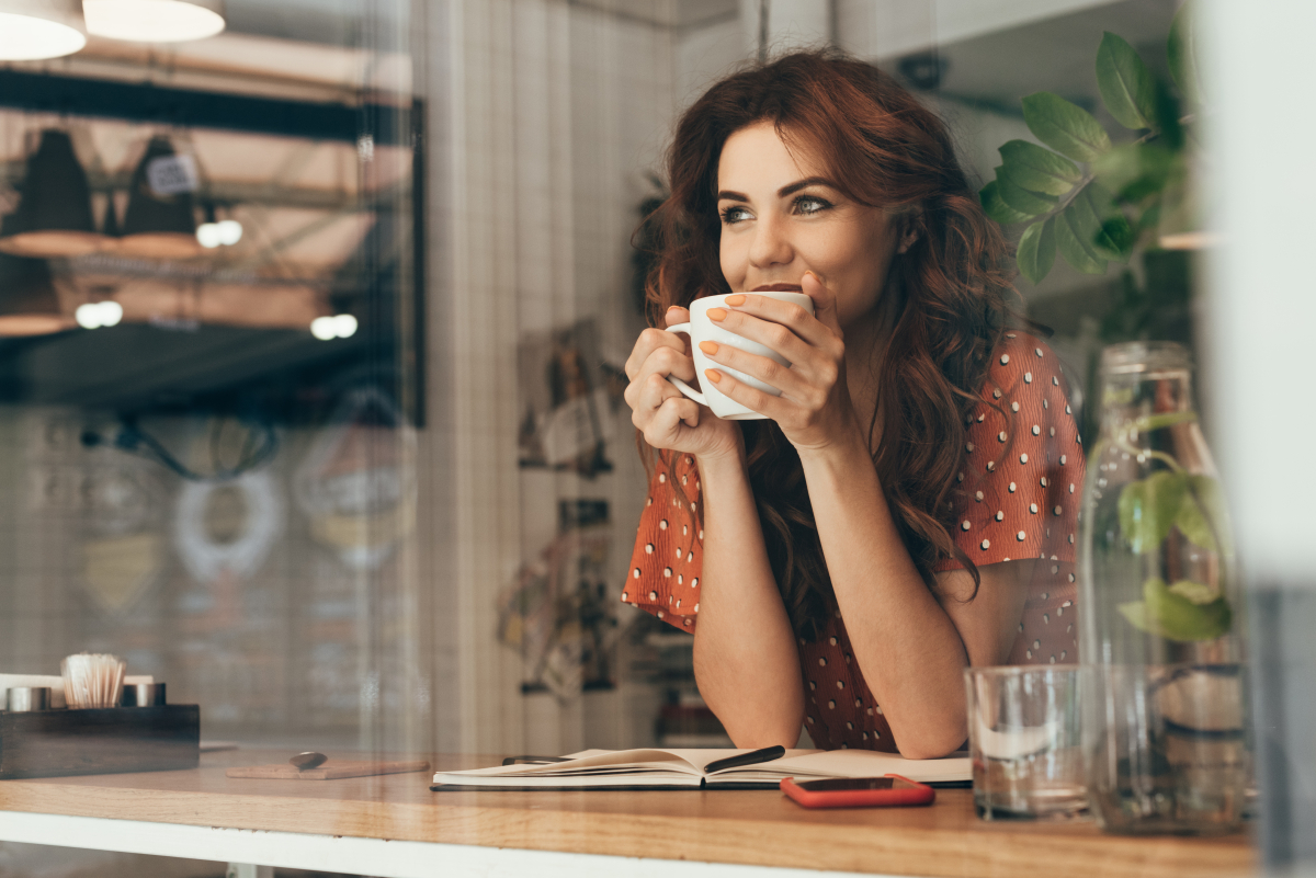 Portrait,Of,Young,Woman,Drinking,Coffee,At,Table,With,Notebook