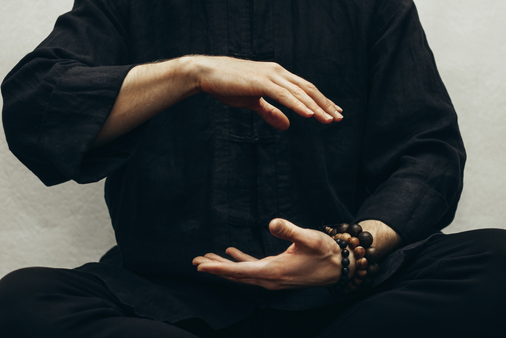 A,Man,In,Black,Shirt,Sitting,And,Doing,Qigong.,Hands