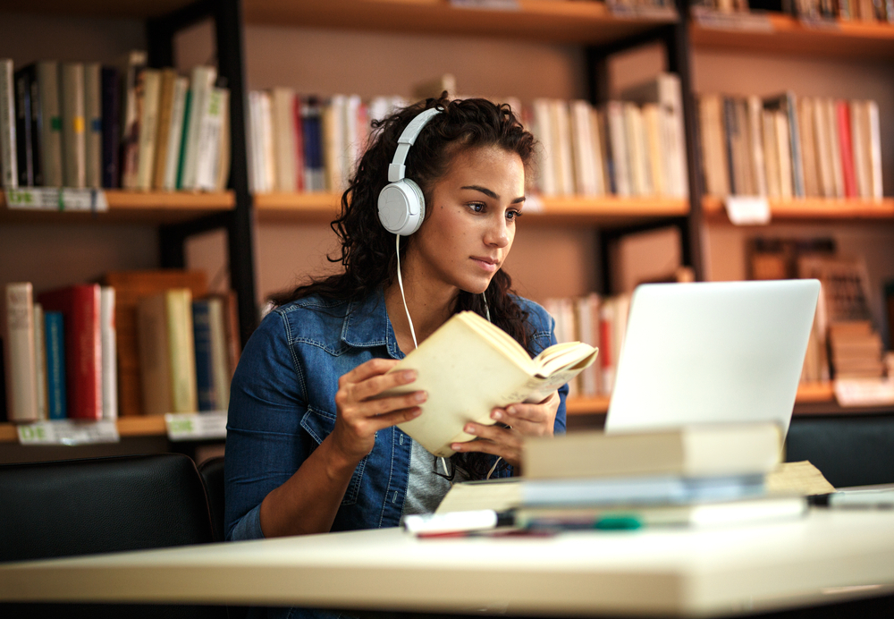 Young,Female,Student,Study,In,The,School,Library.she,Using,Laptop