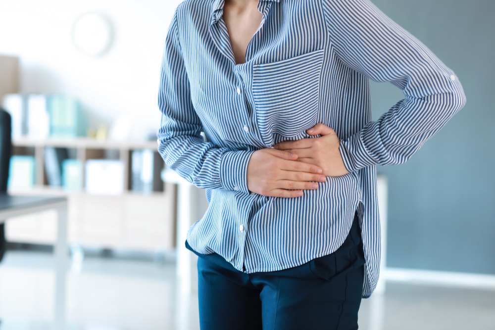 Young,Woman,Suffering,From,Stomachache,In,Office