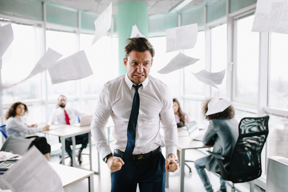Angry,Manager,In,White,Shirt,Standing,Angrily,At,His,Desk.