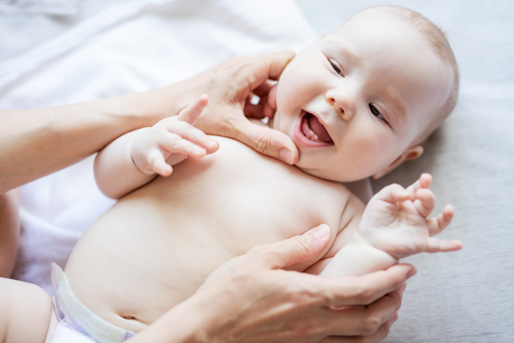 Cheerful,Cute,Baby,Girl,Lying,On,Bed,While,Mother,Looking