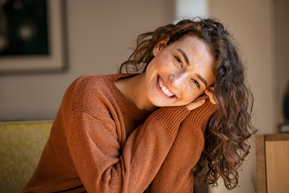 Happy,Young,Woman,Sitting,On,Sofa,At,Home,And,Looking