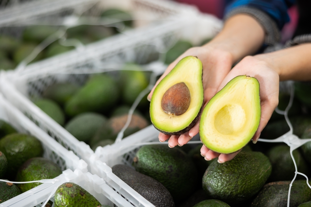 Close-up,Of,Two,Halves,Of,Ripe,Hass,Avocado,In,Hands