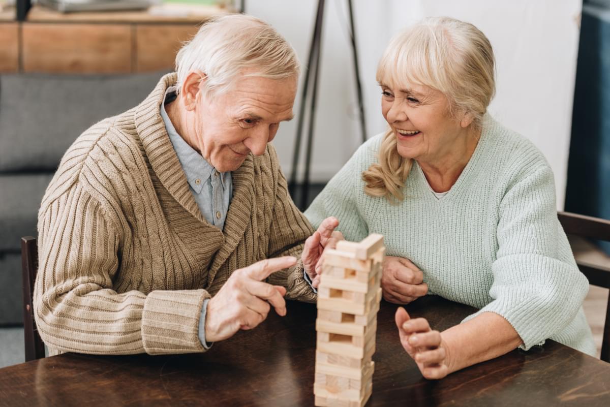 Cheerful,Retired,Husband,And,Wife,Playing,Jenga,Game,On,Table