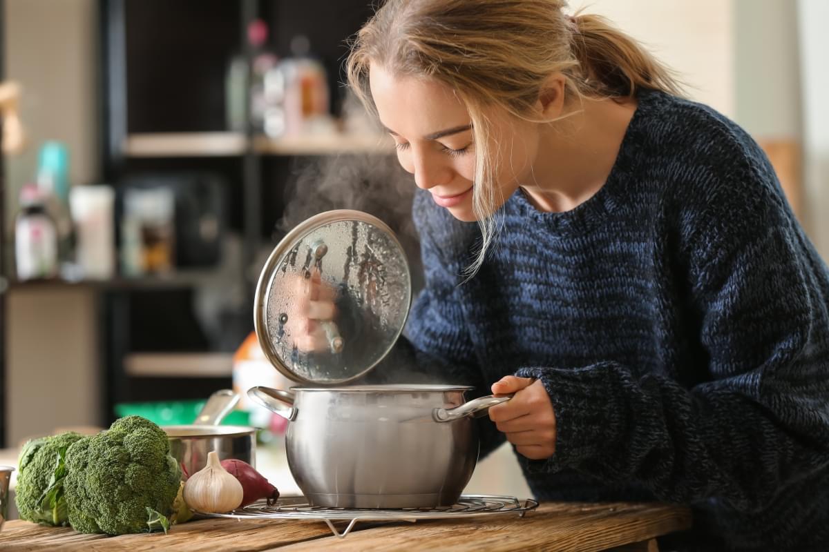 Woman,With,Saucepan,Of,Tasty,Hot,Soup,In,Kitchen